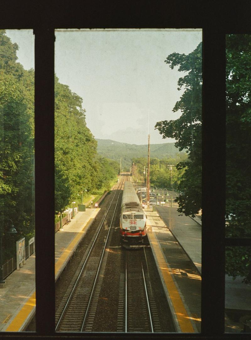 A train approaches from the distance, viewed through a window.