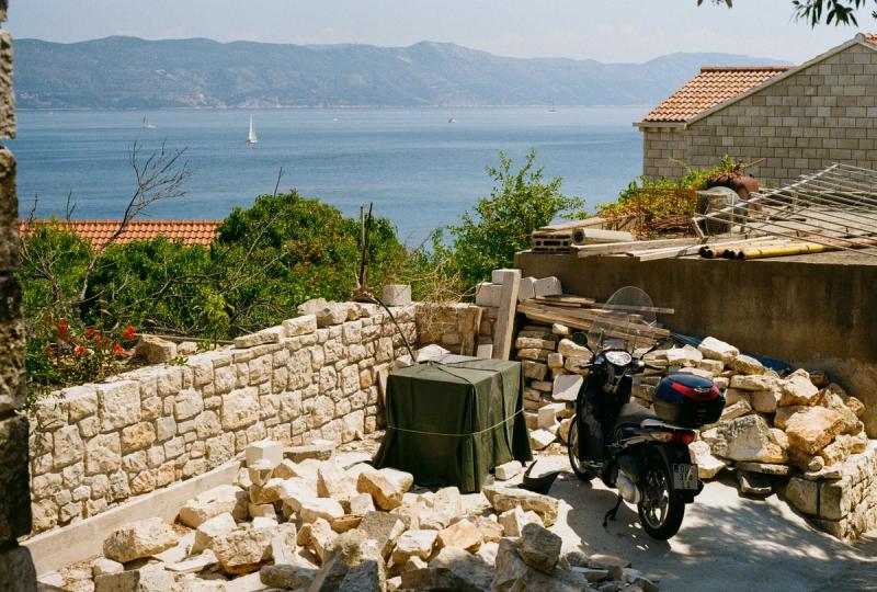 A motorcycle is parked in the middle of a pile of rubble, backdropped by the ocean.