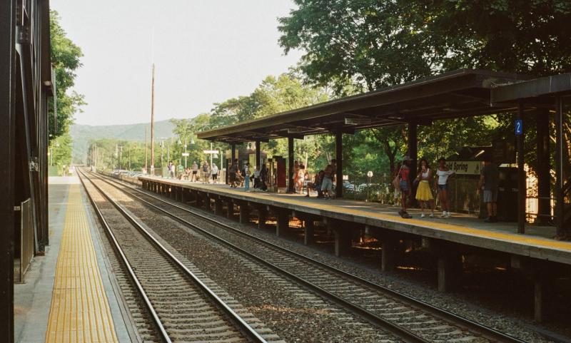 Travelers wait for a train on the platform.