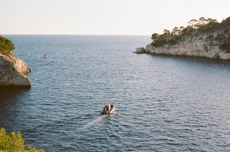 A boat with a trail of wake steers out of a bay.
