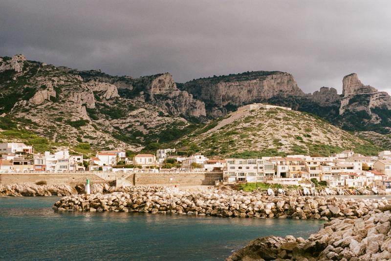 A sun-covered town sits in the foreground, with some dark and foreboding clouds in the background.